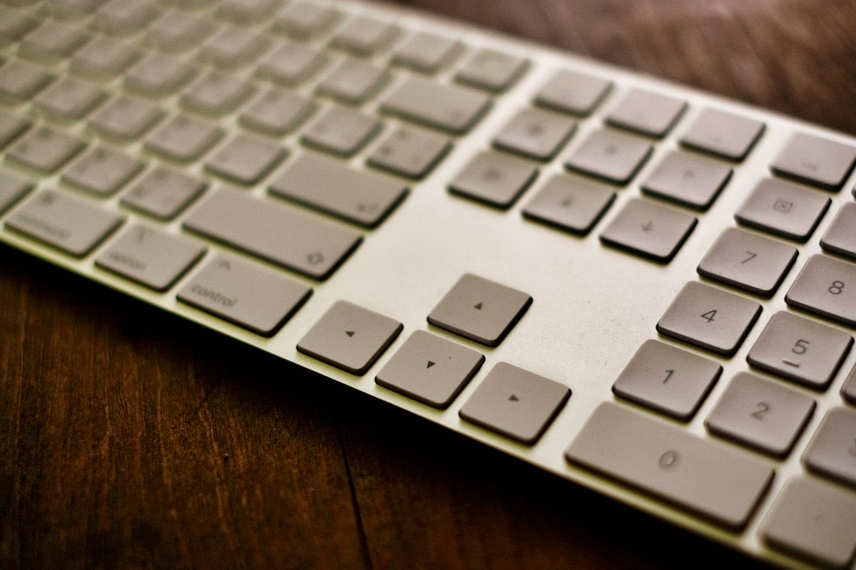 A computer keyboard on a wooden desk, close up