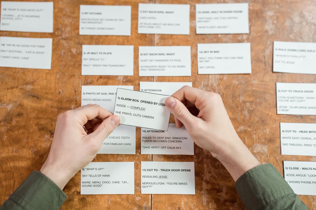 Hands sorting a spread of index cards on a desk