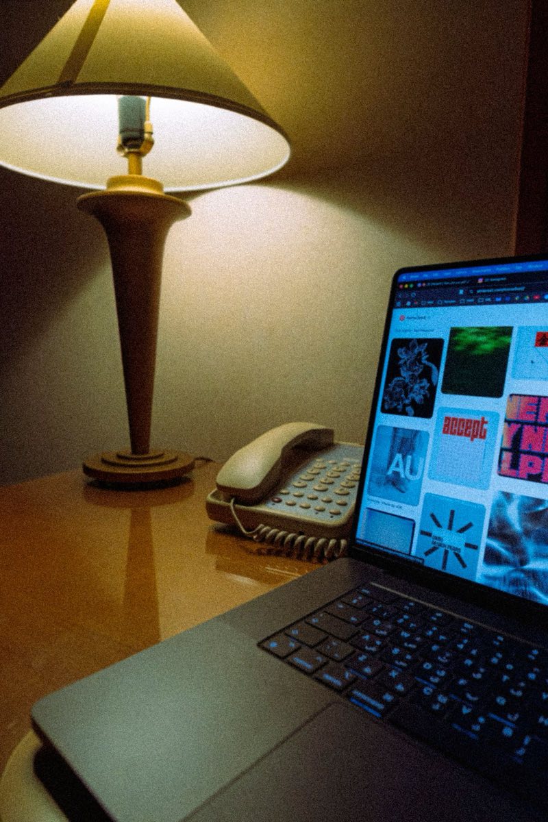 A laptop, desk lamp and telephone on a wooden desk