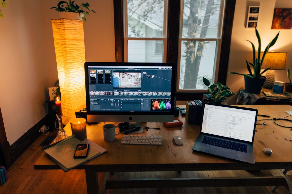 A desk seen from above: laptop, monitor, keypad and phone